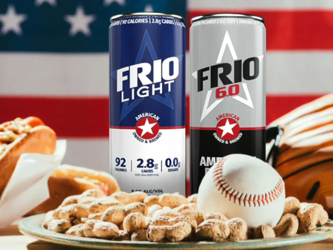 Two cans of Frio Beer, a plate of peanuts, a baseball, and hot dogs in front of an American flag.