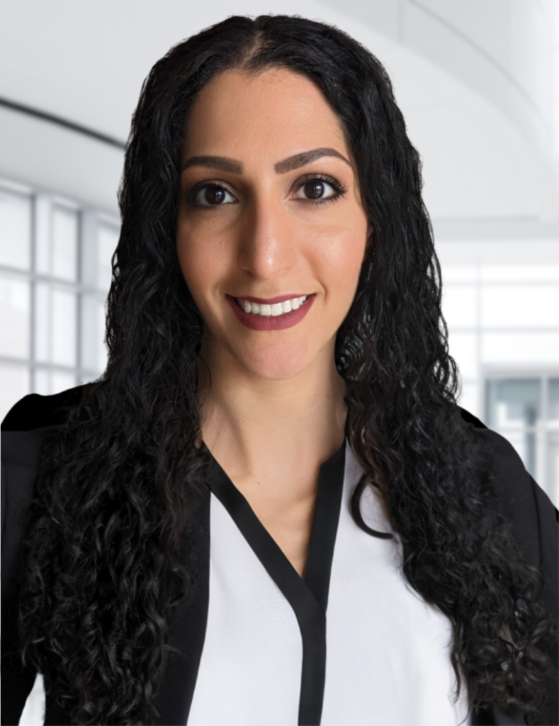 Lilithfoxx smiling at the camera and wearing a business professional suit with a white and black blouse.