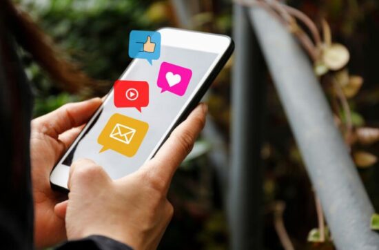 A woman holding her phone with social media marketing icons floating above it.