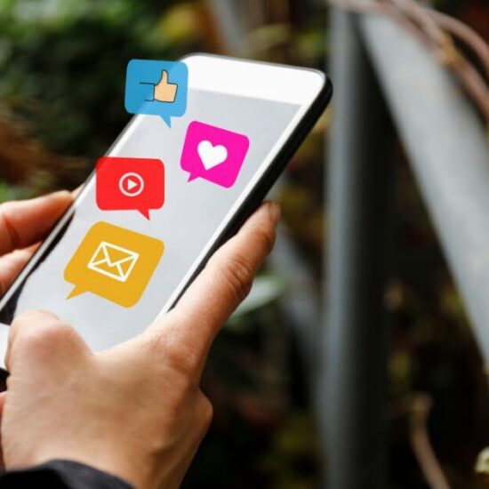 A woman holding her phone with social media marketing icons floating above it.